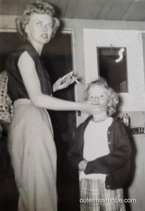 Black and white vintage photo of a lady with a cigarette, shooshing a child. She has her hand over the child's mouth.