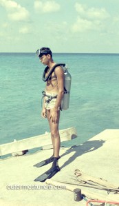 1950's color photo of a deep sea diver. Bahamas. Standing on a pier with spear guns and diving gear. Bermuda Triangle.