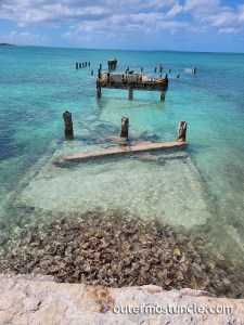 A photo of a large pier, used during the Cold War era, now falling into the turquoise sea.
