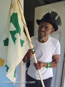 Clifford Fernander a.k.a. Snake Eyes, holds the Ferdinand and Isabella flag on his front porch at Cockburn Town, San Salvador Island, Bahamas.