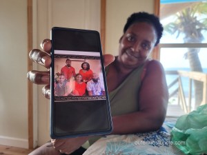 Deidre holds her phone screen toward me. There's a photo of her family on the screen.