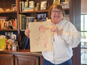 A woman, holding a sketch that was made of her as a child.