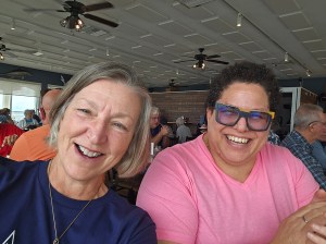 2 smiling women, sitting at a table.