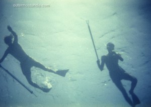A creepy image of 2 divers with spear guns. Taken from below. 1958. Bahamas.