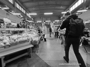 A scene in a Soviet-era market. Shoppers looking at items for sale.