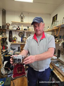 The vendor in an "antik" store at Tallinn's Central Market, holding a Soviet camera I purchased.