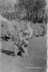 A woman in a bikini in an intimate embrace with a guy who's kneeling.