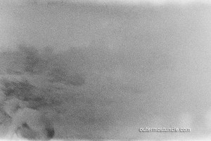 A ghostly photograph of a kid, off center, most likely perusing tidepools.