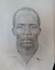 An enlarged passport photo in a frame. A portrait of a black man.