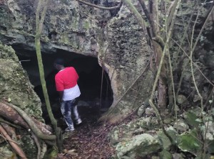 A color photo of a woman, entering a cave.