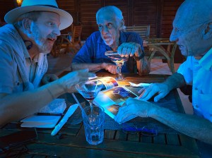 At night in an outdoor bar near Freeport, GBI, we plot our next move. 3 men pour over a book of photos by torchlight. 